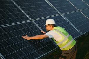 Side view of male worker installing solar modules and support structures of photovoltaic solar array. photo