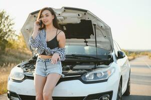 mujer hablando en el teléfono acerca de problema con su coche ella no poder. joven sexy niña consulta en el teléfono durante coche reparar foto