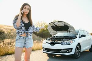 Women talking on the phone about problem with her car she can't. Young sexy girl consults on the phone during car repair photo