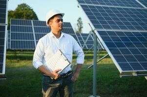 retrato de joven indio masculino ingeniero en pie cerca solar paneles, con claro azul cielo fondo, renovable y limpiar energía. habilidad India, Copiar espacio foto