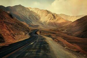 AI generated A scenic view of a curvy asphalt road cutting through arid, majestic mountains with the golden hue of the setting sun illuminating the landscape. photo