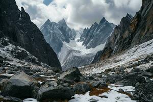 AI generated A breathtaking view of jagged mountains covered in snow, surrounded by rocky terrain under a cloudy sky, evoking a sense of awe and wonder. photo