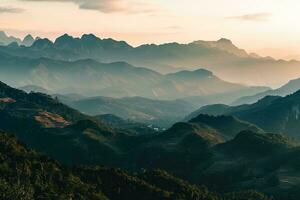 AI generated a breathtaking view of layered mountains veiled in mist, illuminated by the gentle hues of a setting sun, evoking peace. photo