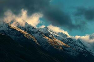 AI generated A dramatic scene of snow-capped mountains under a stormy sky, with the last rays of sun casting a golden glow on the slopes. photo