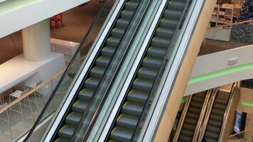 escalera mecánica en un grande de muchos pisos compras centro. alto ángulo vista. yendo arriba y abajo un escalera mecánica con vaso paredes y metal pasos en un escasamente poblado negocio centro. video