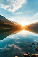 AI generated a stunning sunrise scene. Sun rays pierce through the horizon casting a golden hue. The sun is reflected in a calm and clear lake. Rocks are visible at the edge of the water photo