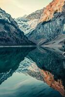 AI generated majestic beauty of nature with a serene alpine lake surrounded by snow-capped mountains and rugged cliffs. The calm waters of the lake perfectly mirror the mountains photo