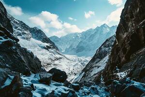 AI generated A breathtaking view of snow-capped peaks, rocky terrain, and white fluffy clouds under a serene blue sky, showcasing nature grandeur. photo