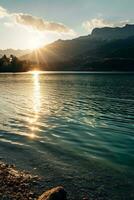 AI generated a stunning natural landscape during sunrise or sunset. A serene lake with crystal clear water reflecting the sky and surrounding scenery. photo