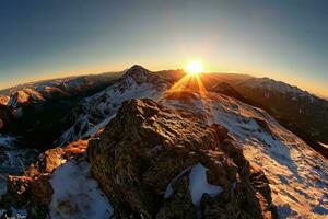 ai generado un asombroso amanecer encima nevadas montañas, fundición un calentar resplandor en el rocoso paisaje, destacando de la naturaleza majestuoso belleza. foto