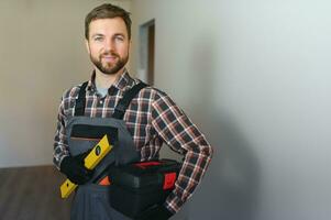 Portrait of a confident repairman with beard standing in empty apartment photo