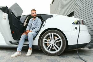 a man charges an electric car photo