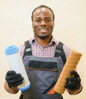 African American plumber holding new and used water filters photo