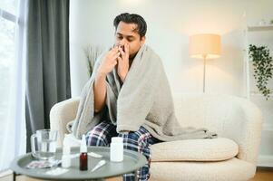 rhinitis, medicine and healthcare concept - sick indian man in blanket using nasal spray at home photo