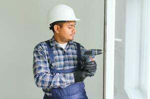 Indian service man installing window with screwdriver photo