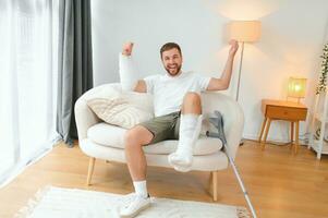 Man with multiple physical limb and body injuries recovers after accident. Happy guy having fun at home photo