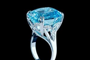 Beautiful gold ring with aquamarine and diamonds on a black background photo
