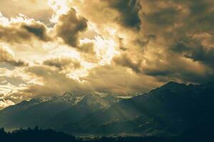 AI generated A dramatic scene unfolds as sunlight breaks through clouds, highlighting snow-capped mountains and casting an ethereal glow over the shadowed photo