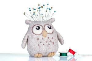 small pillow for needles in the form of an owl with threads on a white background photo