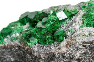 Macro stone garnet mineral, Uvarovite in rock on a white background photo