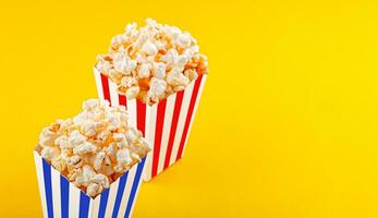 Glass with popcorn on a yellow background photo