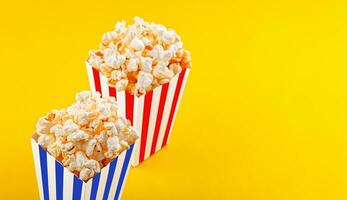 Glass with popcorn on a yellow background photo