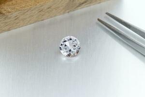 macro mineral faceted stone Morganite with tweezers on a gray background photo