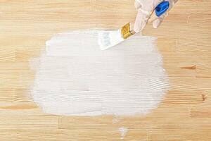 white paint with a brush painting a wooden background with texture photo