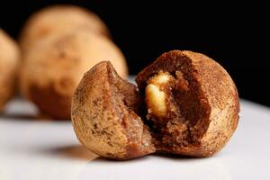 Beautiful candy truffle with a nut inside on a white plate on a black background photo