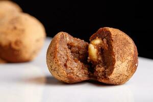 Beautiful candy truffle with a nut inside on a white plate on a black background photo