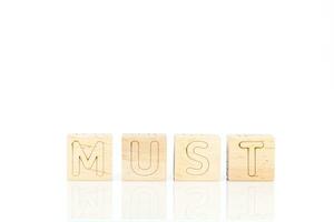 Wooden cubes with letters Must on a white background photo