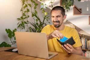 hombre pago con crédito tarjeta en ordenador portátil en línea compras a hogar oficina. foto