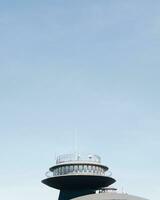 Minimalist photo of a modern tower against a clear blue sky, with ample copy space.