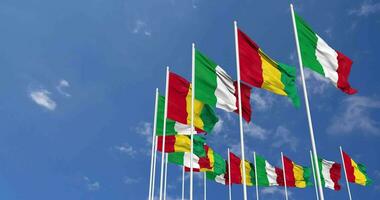 Guinea e Italia bandiere agitando insieme nel il cielo, senza soluzione di continuità ciclo continuo nel vento, spazio su sinistra lato per design o informazione, 3d interpretazione video