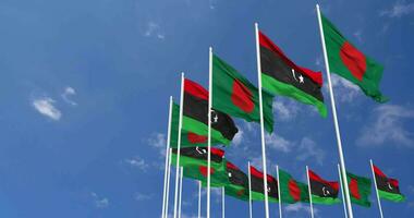 Libia e bangladesh bandiere agitando insieme nel il cielo, senza soluzione di continuità ciclo continuo nel vento, spazio su sinistra lato per design o informazione, 3d interpretazione video