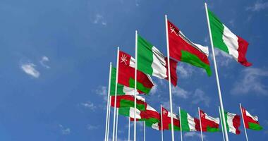 Oman et Italie drapeaux agitant ensemble dans le ciel, sans couture boucle dans vent, espace sur la gauche côté pour conception ou information, 3d le rendu video