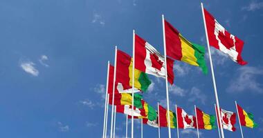 Guinea y Canadá banderas ondulación juntos en el cielo, sin costura lazo en viento, espacio en izquierda lado para diseño o información, 3d representación video