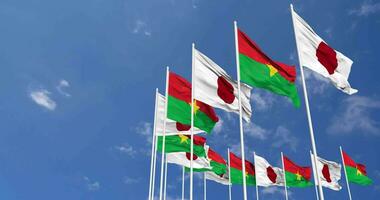 burkina faso et Japon drapeaux agitant ensemble dans le ciel, sans couture boucle dans vent, espace sur la gauche côté pour conception ou information, 3d le rendu video