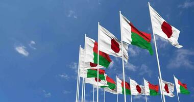 Madagascar e Giappone bandiere agitando insieme nel il cielo, senza soluzione di continuità ciclo continuo nel vento, spazio su sinistra lato per design o informazione, 3d interpretazione video