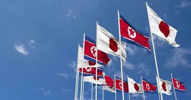 norte Corea y Japón banderas ondulación juntos en el cielo, sin costura lazo en viento, espacio en izquierda lado para diseño o información, 3d representación video