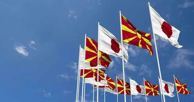 nord macedonia e Giappone bandiere agitando insieme nel il cielo, senza soluzione di continuità ciclo continuo nel vento, spazio su sinistra lato per design o informazione, 3d interpretazione video