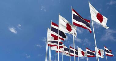 Tailandia e Giappone bandiere agitando insieme nel il cielo, senza soluzione di continuità ciclo continuo nel vento, spazio su sinistra lato per design o informazione, 3d interpretazione video
