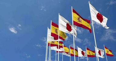 Spagna e Giappone bandiere agitando insieme nel il cielo, senza soluzione di continuità ciclo continuo nel vento, spazio su sinistra lato per design o informazione, 3d interpretazione video