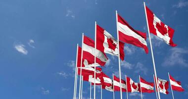 Austria y Canadá banderas ondulación juntos en el cielo, sin costura lazo en viento, espacio en izquierda lado para diseño o información, 3d representación video