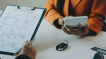 Salesman guiding customer seated at table. Car business. Car sale. Dealership closing. and the new owner has entered into a contract video