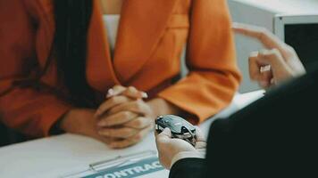 Salesman guiding customer seated at table Car business Dealership closing. and the new owner has entered into a contract video