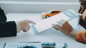 Salesman guiding customer seated at table Car business Dealership closing. and the new owner has entered into a contract video