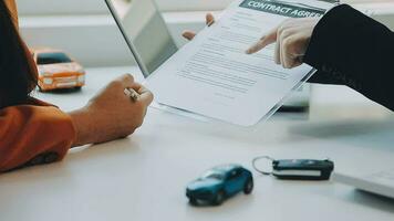 Salesman guiding customer seated at table Car business Dealership closing. and the new owner has entered into a contract video