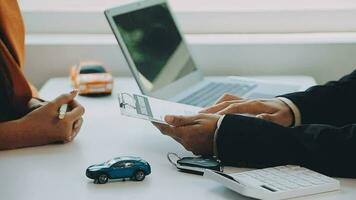 Salesman guiding customer seated at table Car business Dealership closing. and the new owner has entered into a contract video