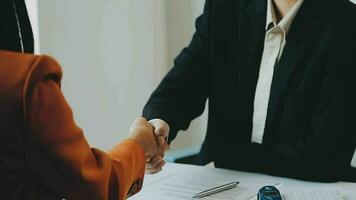 Salesman guiding customer seated at table Car business Dealership closing. and the new owner has entered into a contract video